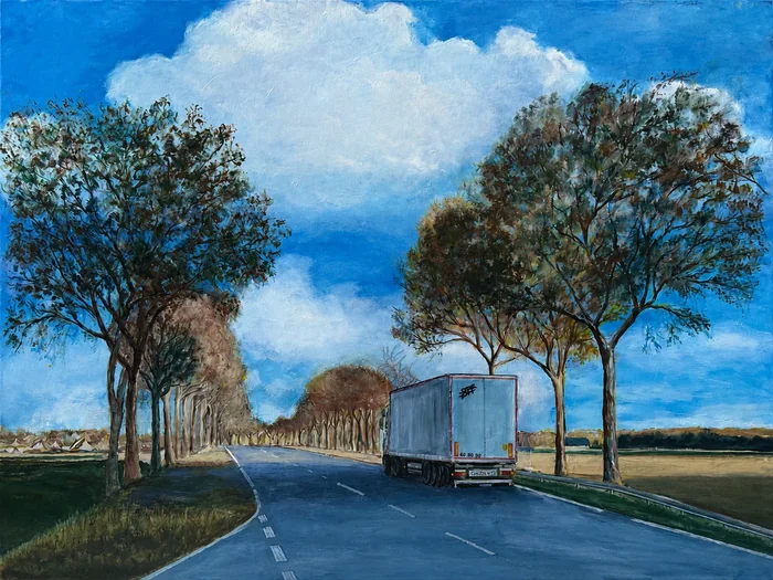 Un camion avance sur une route bordée d’arbres sous un ciel ouvert